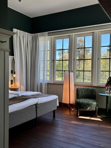 a bedroom with a bed and a chair and windows at Lilla Hotellet Blidö in Blidö