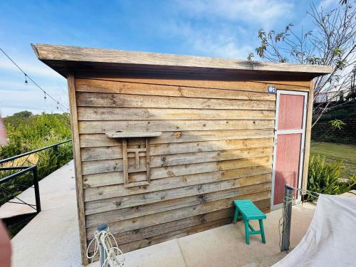 a small wooden building with a door and a green bench at DaLart Glamping & Coffee in Ấp Ða Lôc