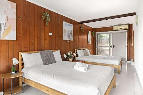 two beds in a room with wooden walls at Simple 2-Double Bed Studio Stay at Peakhurst in Peakhurst