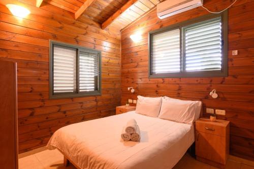 a bedroom with a bed with two towels on it at בינות התמרים- 3 צימרים מהממים עם בריכה וג'קוזי ספא! in Menaẖemya