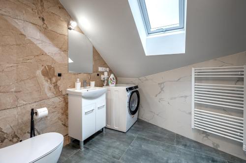 a bathroom with a sink and a washing machine at Apartmány Vulcano in Perná
