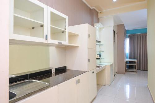 a kitchen with white cabinets and a sink at Sans Hotel International Surabaya in Gubeng