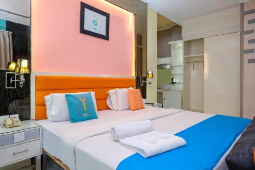 a bedroom with a large bed with colorful pillows at Sans Hotel International Surabaya in Gubeng