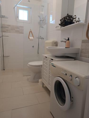 a white bathroom with a washing machine and a sink at Apartments Biba & Lucy in Ražanac