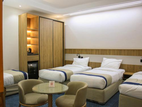 a hotel room with three beds and a table and chairs at فندق برج جزيرة العرب in Medina