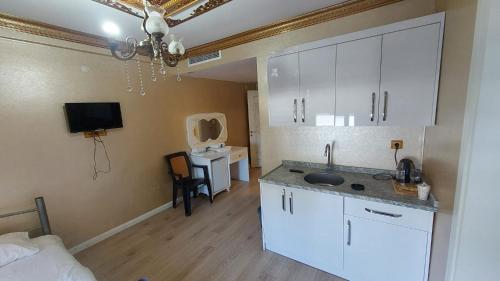 a kitchen with white cabinets and a sink in a room at Aksu Otel in Aliağa