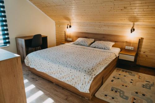 a bedroom with a bed and a desk and a chair at Nordic Cabin in Bughea de Jos