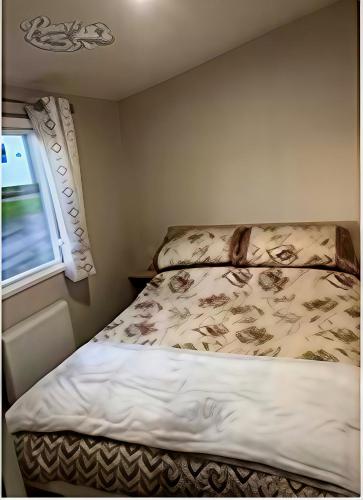 a bedroom with a bed and a window at Panacci Van - Weymouth Bay in Preston