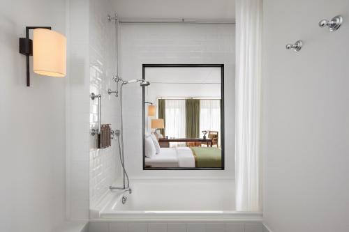 ein Badezimmer mit Badewanne und Spiegel und ein Schlafzimmer in der Unterkunft Louis Hotel in München