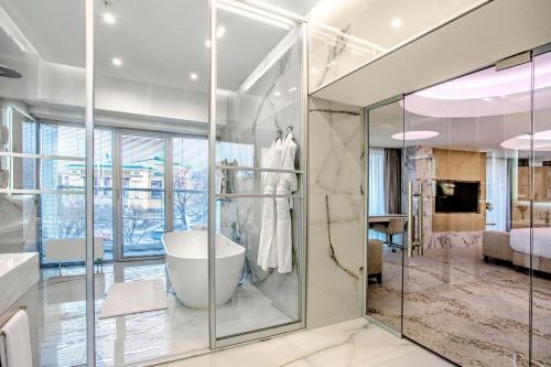 a bathroom with a bath tub and a bedroom at Almaty Hotel in Almaty