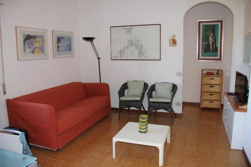 a living room with a red couch and two chairs at Castiglione Della Pescaia in Castiglione della Pescaia