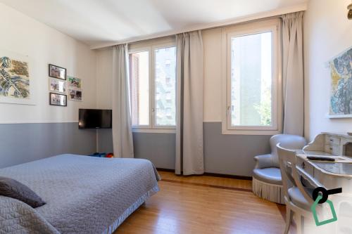 a bedroom with a bed and a chair and two windows at Hotiday Milano CityLife in Milan