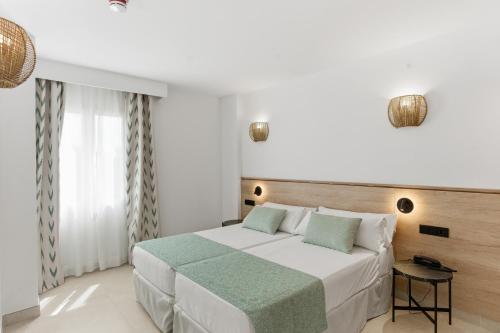 a bedroom with a large white bed and a window at Aquasol Aparthotel in Palmanova
