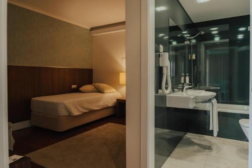 a bedroom with a bed and a sink and a mirror at Quinta do Pinheiro Hotel E Eventos by Grupo Quinta dos Lagos in Valado dos Frades