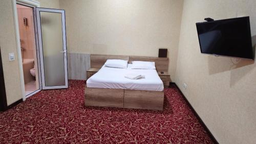 a hotel room with a bed and a flat screen tv at Sitora in Chirchiq