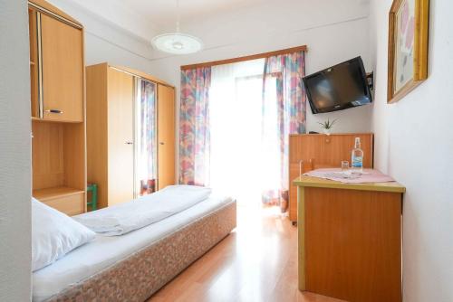 a hotel room with a bed and a television at Strandhotel Pichler in Seeboden