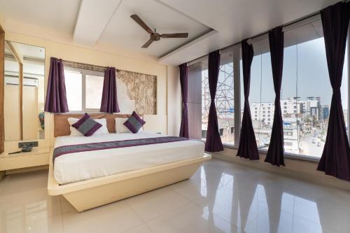 a bedroom with a bed with purple curtains and windows at Devbhoomi Inn in Deoghar