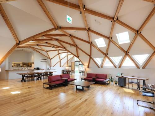 a large room with wooden ceilings and red chairs and tables at 友愛ファームゲストハウス in Hatoyama