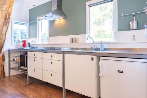a kitchen with white cabinets and a sink at De Toffe Peer Recreatie in Ruinerwold