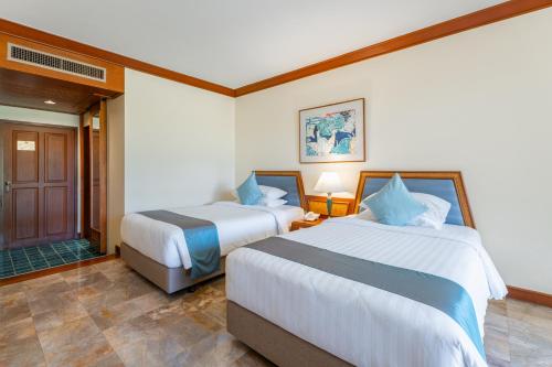 a bedroom with two beds and a door to a bathroom at Maneechan Resort - SHA Extra Plus in Chanthaburi