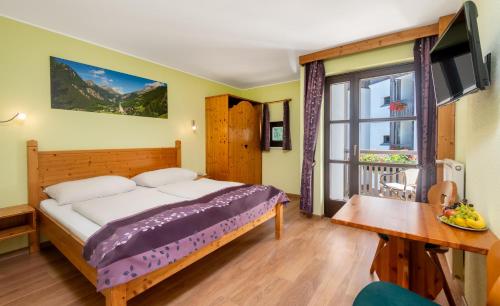 a bedroom with a bed and a television and a table at Sporthotel Heiligenblut in Heiligenblut