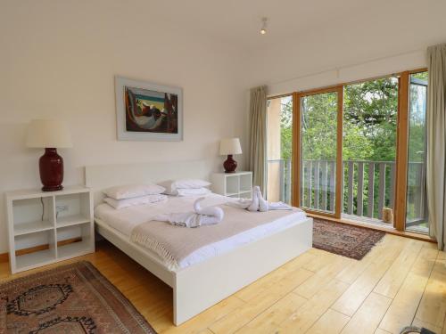 a white bedroom with a bed and a balcony at Frater House in Alburgh