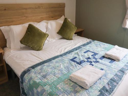 a bed with two pillows and a quilt on it at Jurassic Discovery in Charmouth