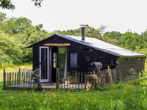 a small shack in a field of grass at The Old Apple Shed cosy heated cottage in a meadow close to the charming village of Bethersden in Ashford