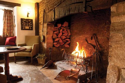 a living room with a fireplace with a pile of logs at Old Swan in Minster Lovell