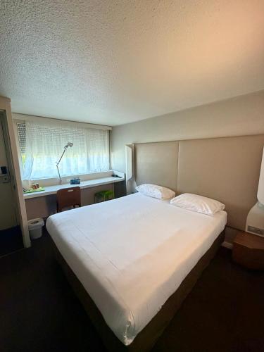 a bedroom with a large white bed and a window at Campanile Chambéry in Chambéry