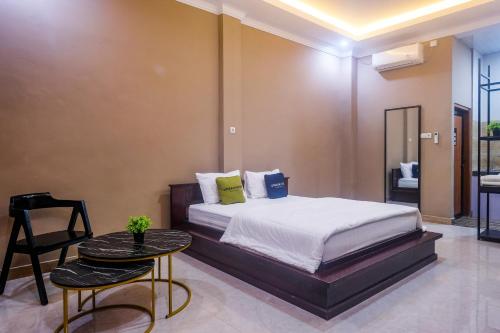 a bedroom with a bed and a table and a chair at Urbanview TWH Costel near Stadion Maguwoharjo Yogyakarta in Yogyakarta