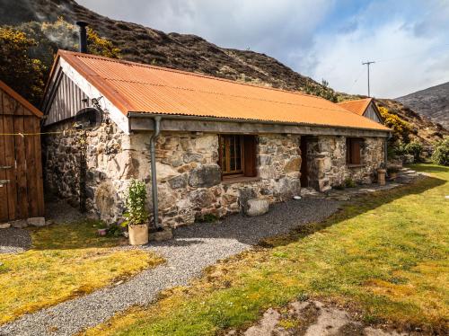 an old stone cottage with an orange roof at Mullach Dearg in Tarbert