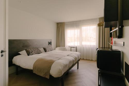 a bedroom with a large bed and a window at Boutique Hotel Herbergh Amsterdam Airport FREE PARKING in Badhoevedorp