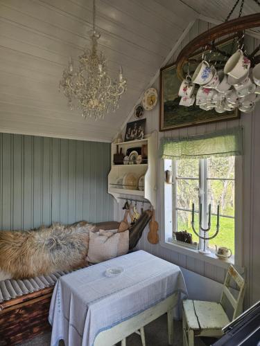 a living room with a table and a chandelier at Hammergaarden Stabbursstua - Heritage Loft Stay in Sortland