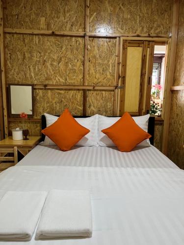 a bedroom with a bed with two orange pillows at SDD HoSTEL in Thung Si Kan