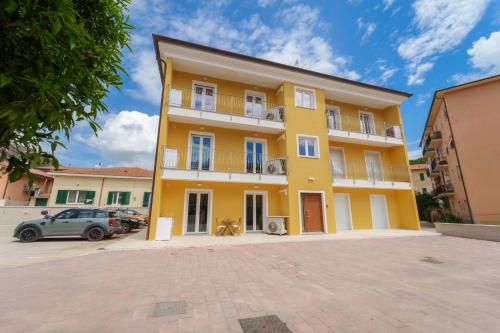 a yellow building with cars parked in front of it at Appartamento Mavi in Porto Azzurro