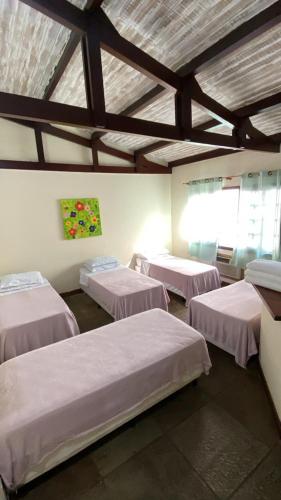 a room with four beds in a room with a ceiling at Pousada Icaraí Inn in Niterói
