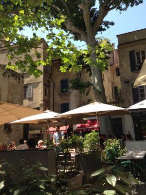 un groupe de personnes assises sous des parasols dans une rue dans l'établissement Appartement Maison Aubanel, à Avignon