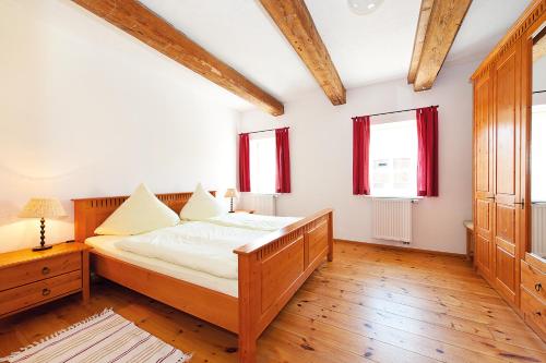 a bedroom with a wooden bed and two windows at Alter Gutshof Papstdorf in Papstdorf