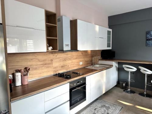 a kitchen with white cabinets and a wooden counter top at White Sand Apartment Valamar 2 Bedroom Balcony Parking in Draç