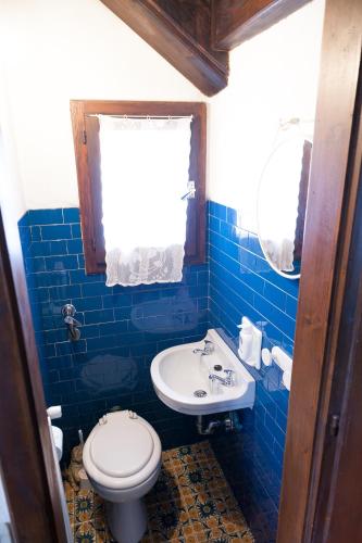 a blue tiled bathroom with a toilet and a sink at Casa Remo 1 in San Vito di Cadore