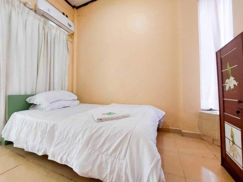 a bedroom with a bed with white sheets and a window at Quattrick Dee Homestay Mitra RedDoorz in Manokwari