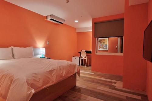 a bedroom with orange walls and a bed and a desk at Happy Inn in Taichung