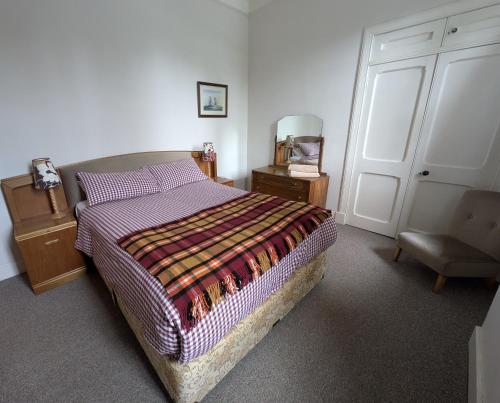 a bedroom with a bed and a chair and a door at Strathpeffer Holiday Cottages in Strathpeffer