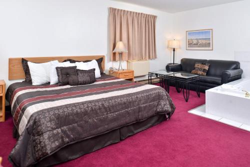 Una habitación de hotel con una cama grande y un sofá. en Sauk River Inn & Suites, a Travelodge by Wyndham, en Sauk Centre