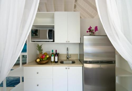 a kitchen with white cabinets and a stainless steel refrigerator at Bequia Plantation Hotel in Bequia