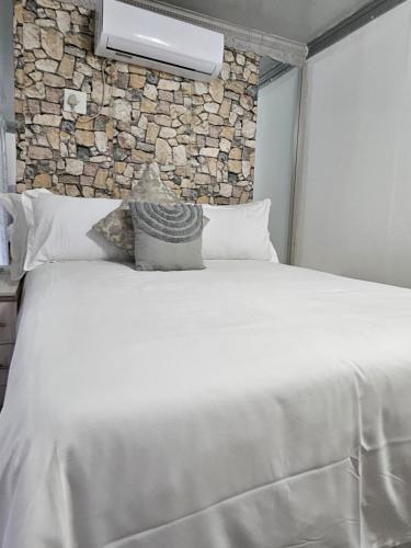 a bedroom with a large white bed with a stone wall at Elitha Boutique Bed and Breakfast in Mogwase