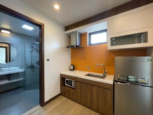 a kitchen with a sink and a refrigerator and a shower at ZEN RIVERSIDE HOTEL & RESIDENCES in Hai Phong