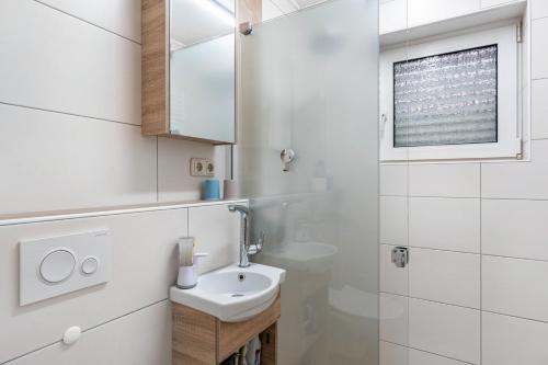 a white bathroom with a sink and a mirror at Ferienwohnung Henrich in Hooksiel