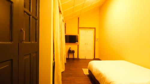 ein gelbes Zimmer mit einem Bett und einer Tür in der Unterkunft Colonial 44 in Kohīma